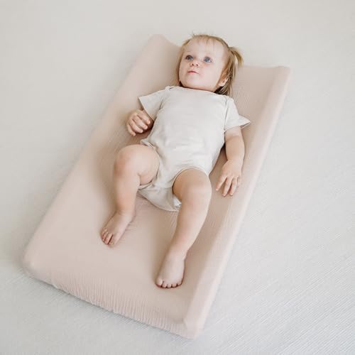 Side angle shot demonstrating the snug fit of the clay toned MairMore cotton sheet over a nursery table pad.