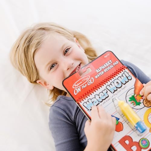 Close up of a child using the water pen to reveal colorful letters on the spiral bound pages.