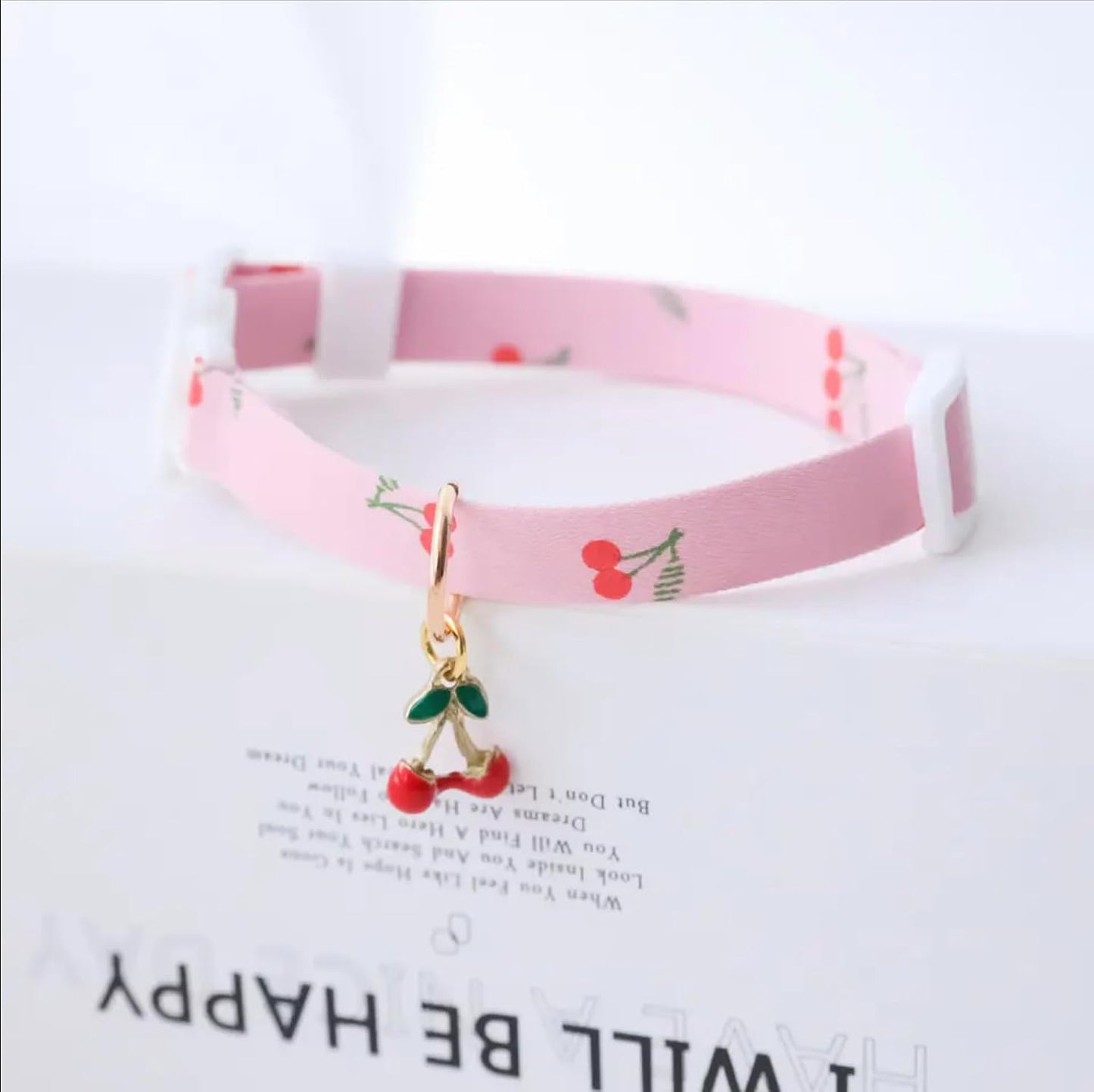 Close up of decorative kitty and cherry charms on matching feline safety collars