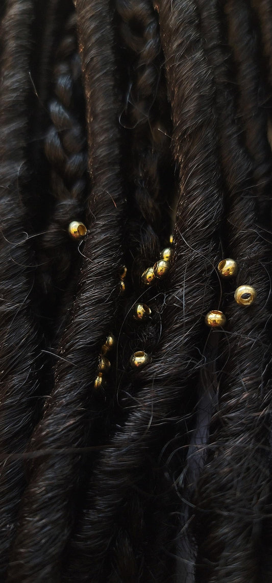 Close up view of sterling silver plated brass 3mm micro hair jewelry pieces on a plain background