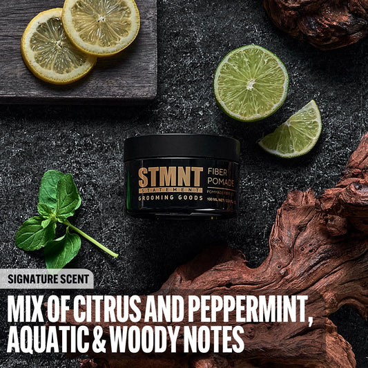Open jar of STMNT Fiber Pomade displaying the gold colored elastic fiber formula texture