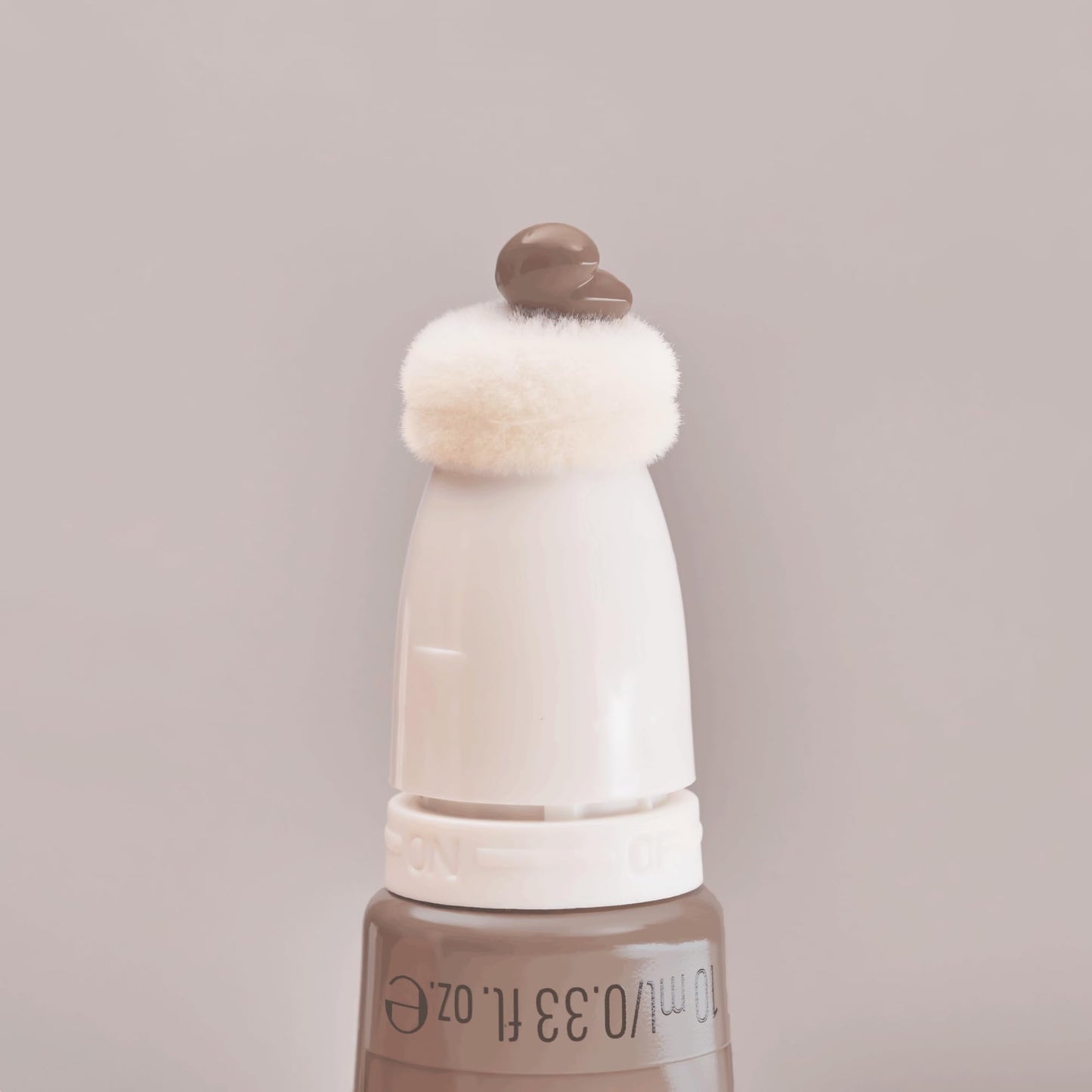 A lifestyle shot of the authentic imported Essence liquid bronzer placed with other clean beauty products.