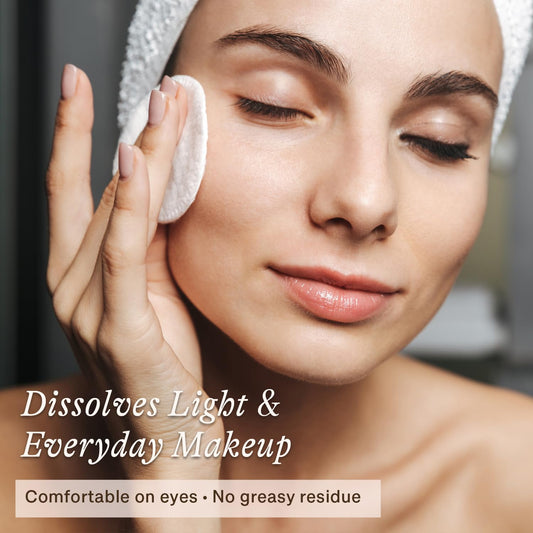 Natural eye and face makeup remover liquid poured on a reusable cotton pad