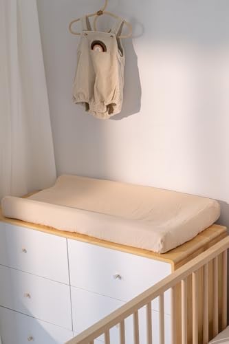 Infant nursery setup featuring neutral teddy bear and khaki patterned change mats