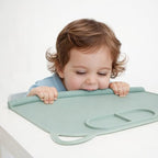 Demonstration of the flexible green Domensi silicone placemat being rolled up tightly to fit inside its matching canvas storage bag.