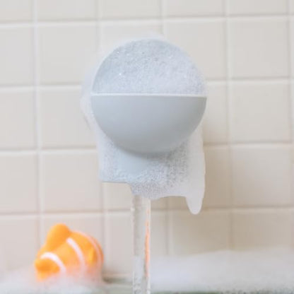 Toddler enjoying a safe bath with the grey Munchkin faucet protection guard.