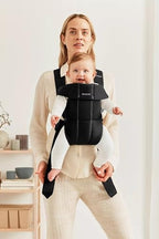Infant sitting safely inside the BabyBjorn black woven newborn carrier close-up
