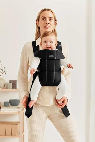 Infant sitting safely inside the BabyBjorn black woven newborn carrier close-up
