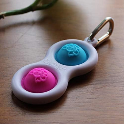 An adult holding the Fat Brain Toys Simpl Dimpl fidget tool to demonstrate size