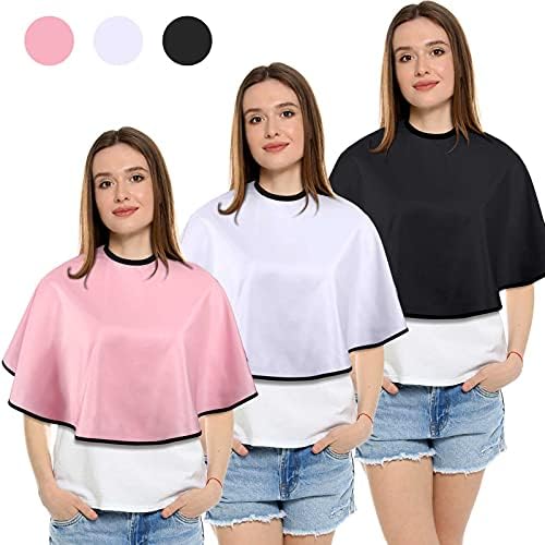 Three pieces of shorty salon smocks with adjustable neck buckles laid out flat.