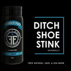 Travel size shoe freshener bottle being squeezed into a pair of athletic sneakers.