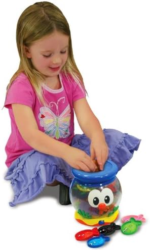 Toddler hand inserting a colored fish piece into the top slot of the interactive preschool learning toy.