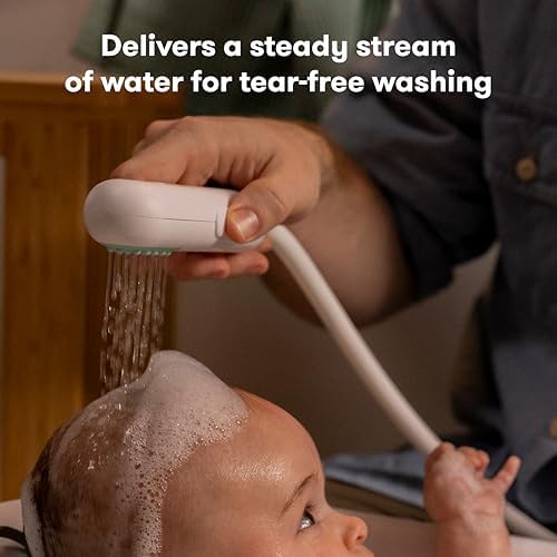 Frida Baby electric suction pump and long hose attachment secured to a baby bathtub floor for continuous water flow.