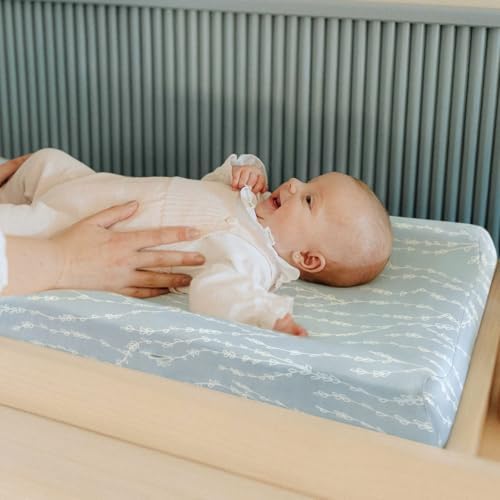 Side angle view of the elastic band securing the cover tightly onto a standard changing table pad.