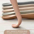 The bendable handle of a pink NETANY baby spoon being flexed to demonstrate structural durability.