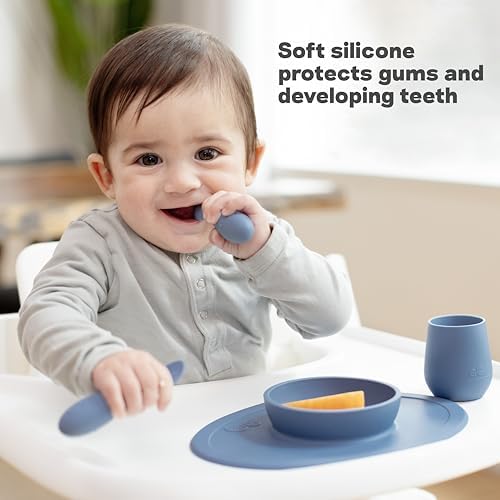The two sage green baby weaning utensils resting on a highchair tray.