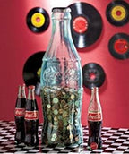 Side angle view of the two foot tall transparent Coca-Cola savings container filled with various coins.
