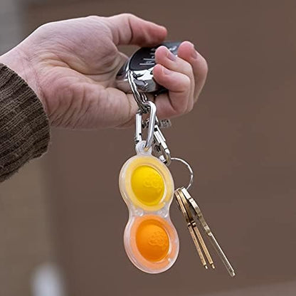 Adult holding the transparent sensory toy between fingers demonstrating the popping function for stress relief.