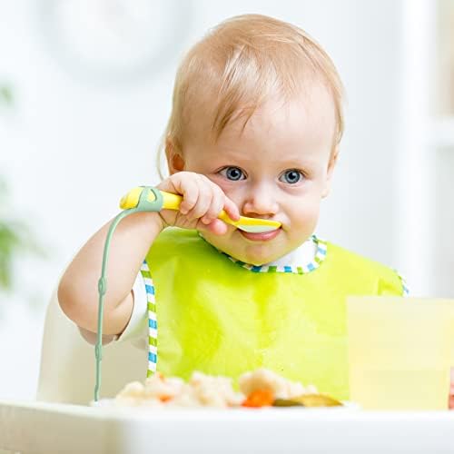 Infant sitting in a highchair using the flexible weaning strap to keep a self feeding utensil off the floor.