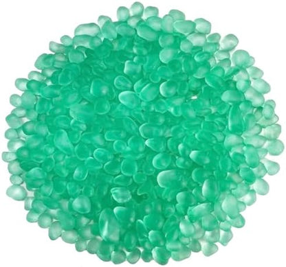 Smooth green sea glass pebbles arranged inside a small fish tank showing underwater clarity and shimmer