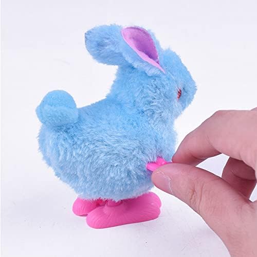 Toddler hand winding the clockwork spring mechanism of a beige bunny toy.