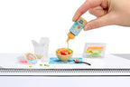 Miniature cafe food replica from Miniverse Series 6 being cured under UV light.