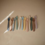 Two pack of Mushie food-grade silicone baby weaning cutlery displayed on a neutral background.