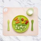 Compact blueberry silicone dining mat for infants next to its portable storage container
