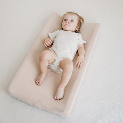 Side angle shot demonstrating the snug fit of the clay toned MairMore cotton sheet over a nursery table pad.
