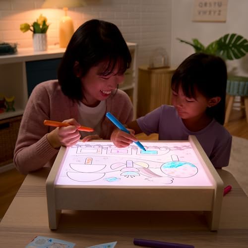 Sensory bin accessory filled with fine motor tools and measuring cup over illuminated base.