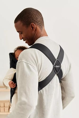 Side profile of a parent wearing the BabyBjorn woven black infant carrier