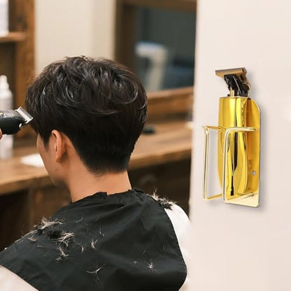 Gold finished metal trimmer storage stand mounted on salon wall holding electric hair clippers securely