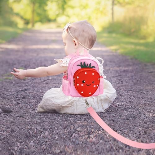Child using strawberry backpack with security rein in park