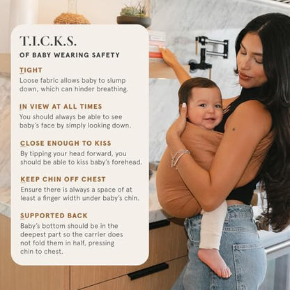 Side view of a newborn securely seated in the hip healthy WildBird carrier