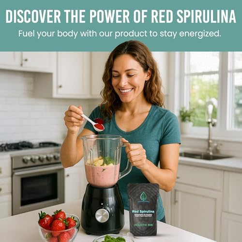 Raw red spirulina powder being added to a green smoothie blender