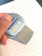 HERKLIN Terminator stainless steel comb held by hand demonstrating ergonomic control.
