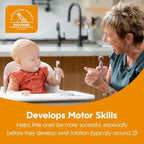 An infant safely holding the thick contoured handle of the gray toddler self feeding utensil.