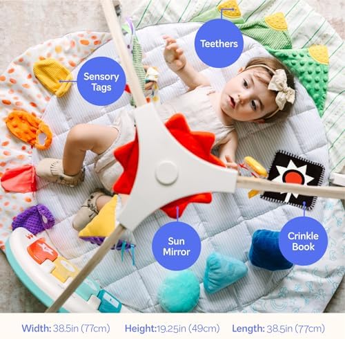 Infant playing with musical piano and sensory toys on gym mat