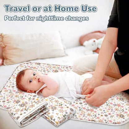 Infant lying comfortably on the floral pattern portable changing cushion during a diaper change.
