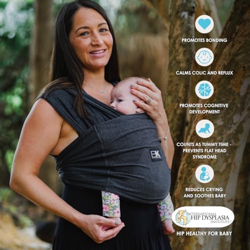 Parent wearing the black Baby K'tan Active carrier outdoors showing sun protection usage