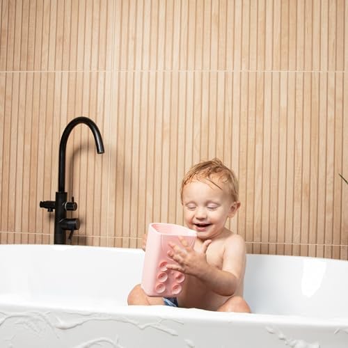 Toddler playing with pink Rinzee baby bath cup exploring the suction cup functionality during bath time.