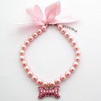PetFavorites fancy pearls crystal dog necklace front view featuring pink ribbon bow and rhinestone bone charm.