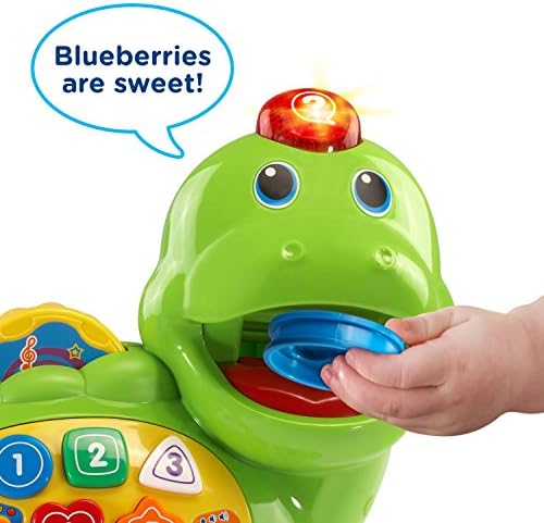 VTech electronic dinosaur toy with eight colorful food pieces spread out