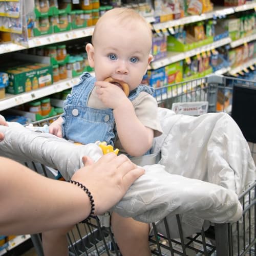 Infant sitting safely inside the cushioned neutral grey leaf print shopping cart cover