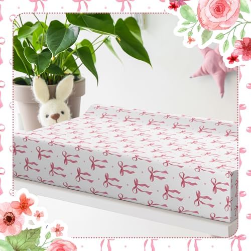 Aesthetic nursery decor setting featuring the pink bow pattern changing mattress sheet.