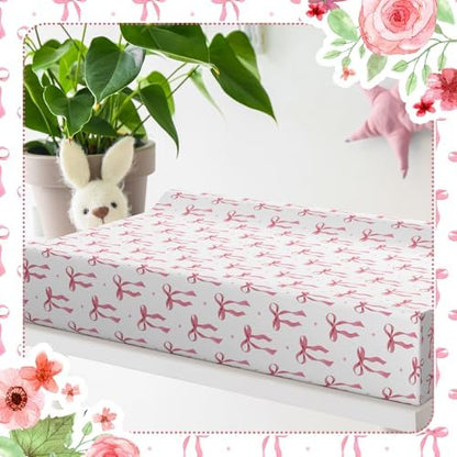 Aesthetic nursery decor setting featuring the pink bow pattern changing mattress sheet.