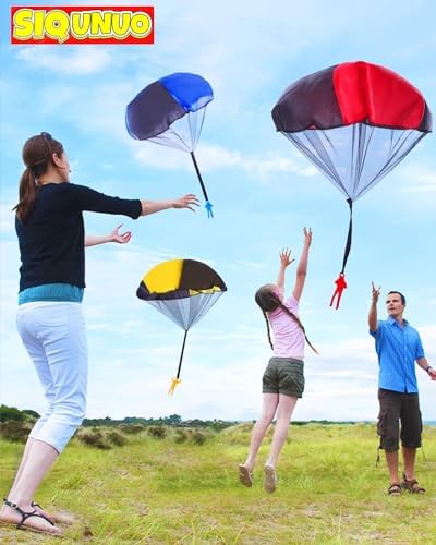 Multiple vibrant paratrooper toys floating down gracefully in an open park.