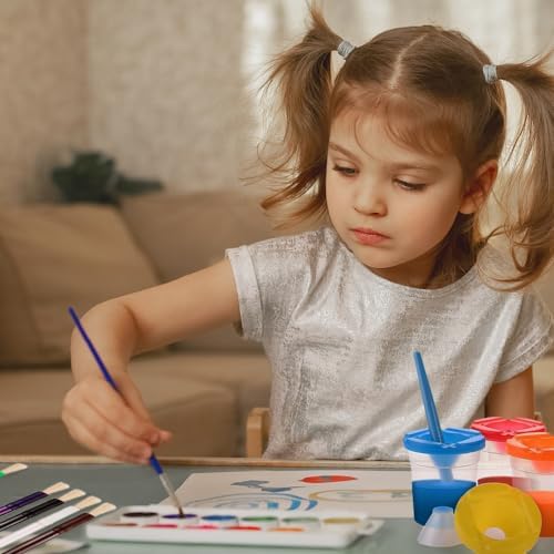 Spill proof painting containers with matching colored lids and thick plastic toddler brushes arranged on a white activity table
