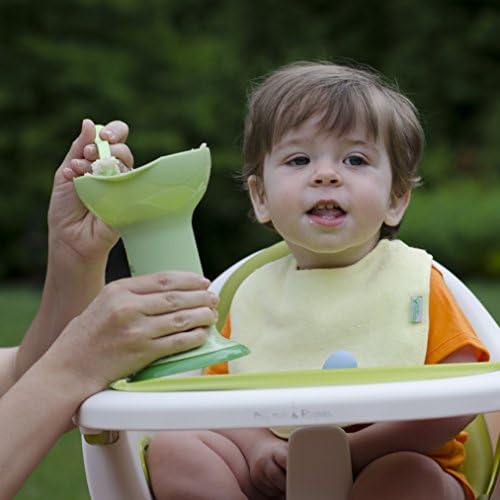 Green Sprouts portable baby food mill being packed into a travel bag for outdoor use.