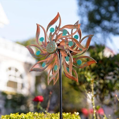 Assembled outdoor garden pinwheel standing upright on a sturdy metal stake inside a lush green lawn.